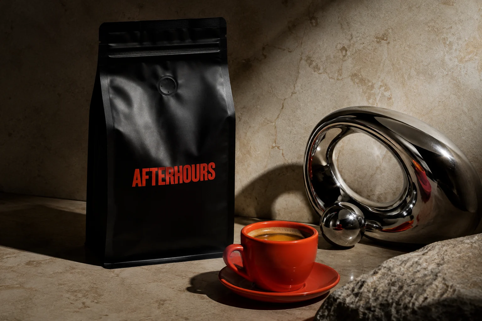 Fictional AFTERHOURS black coffee packaging and an orange espresso cup beside polished chrome on limestone.